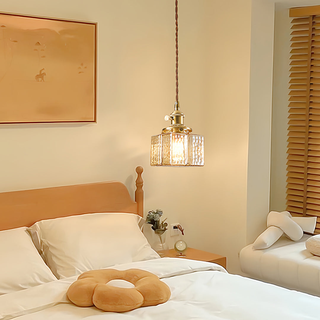 Square glass pendant lights in elegant bedroom with brass hardware providing warm ambient lighting beside natural wood