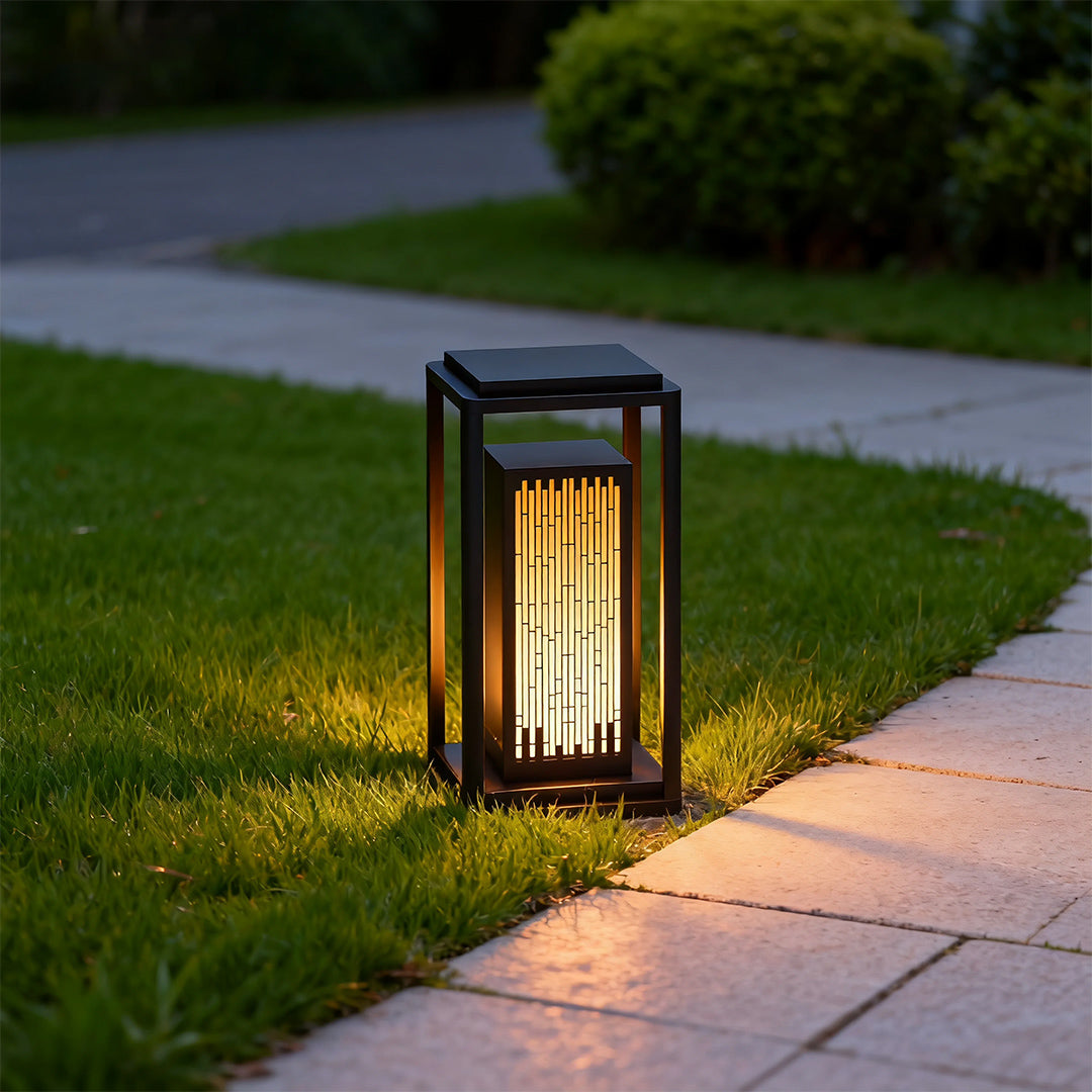 Square outdoor lantern installed along a garden pathway, providing warm and inviting illumination.
