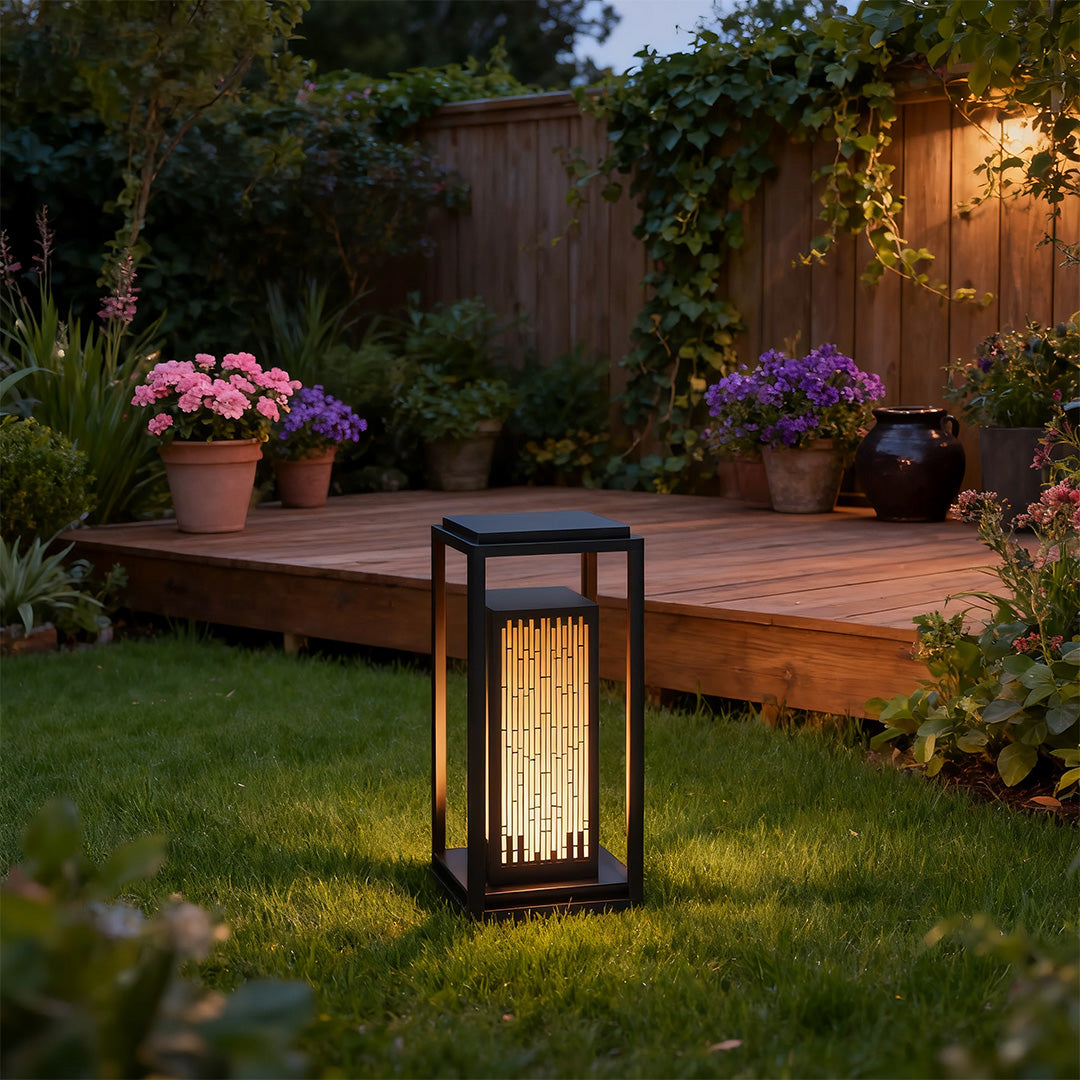 Square outdoor lantern in a garden with plants, adding a contemporary touch to the outdoor space.