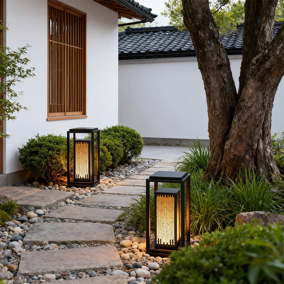 Square outdoor lantern in a garden with plants, adding a contemporary touch to the outdoor space.