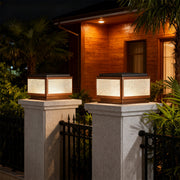 Square outdoor pillar light along a pathway near a modern house, offering stylish and functional lighting.