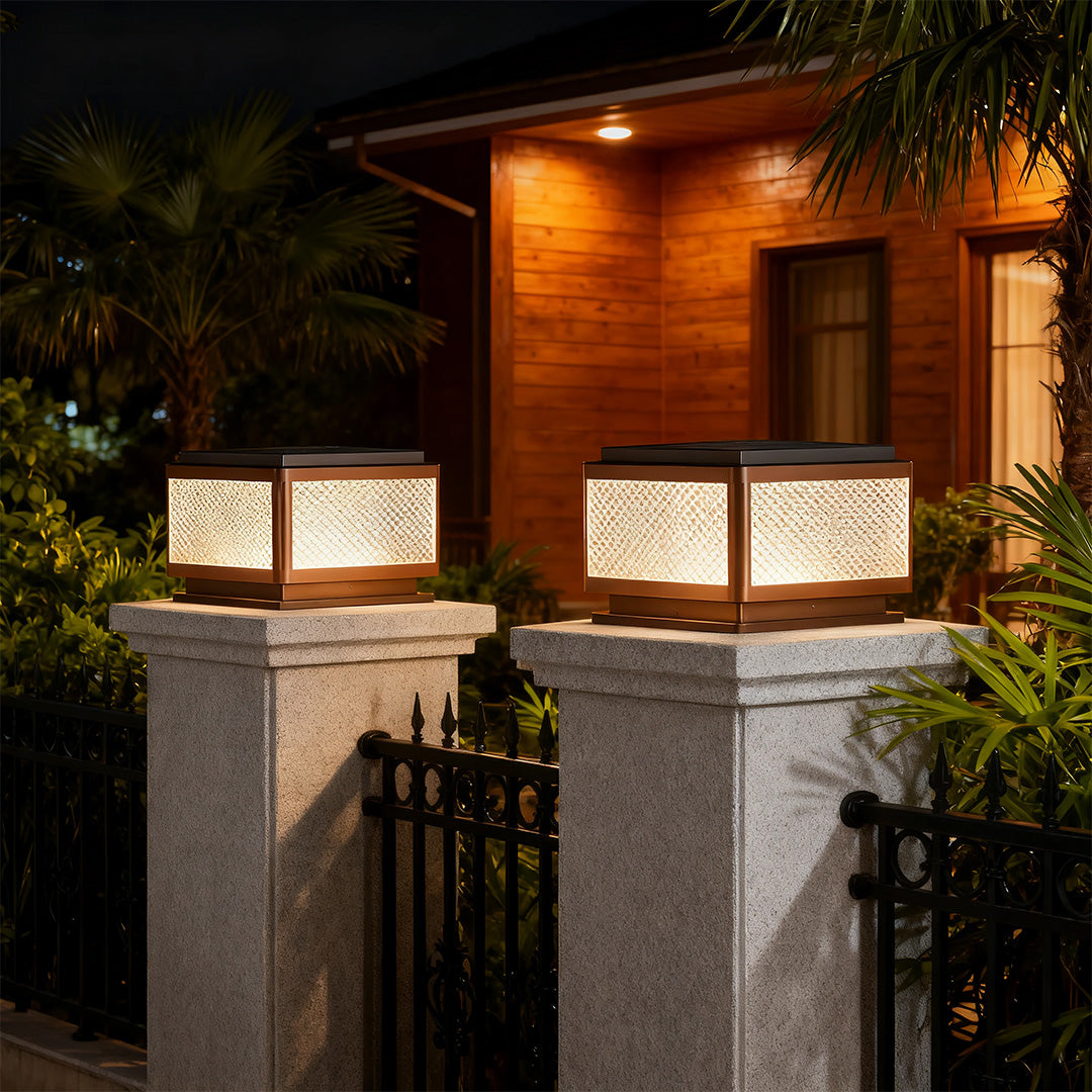 Square outdoor pillar light along a pathway near a modern house, offering stylish and functional lighting.