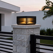 Square outdoor pillar lights installed on stone post providing warm ambient lighting in landscaped garden daytime.