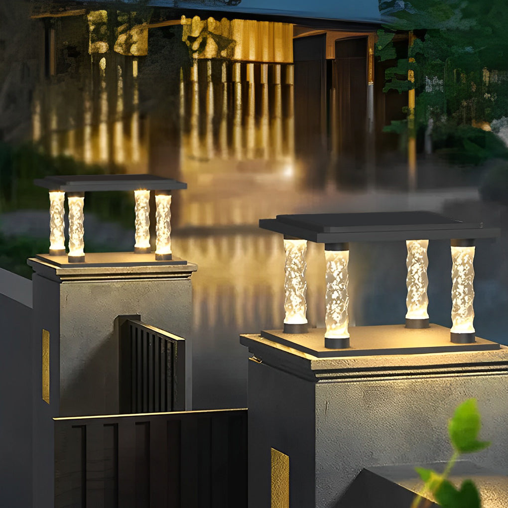 Square pillar lamp with crystal columns, providing ambient light near a fence.