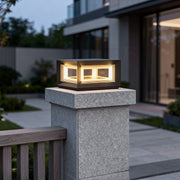 Modern square pillar lights mounted on a concrete gate post, emitting warm light to highlight a contemporary residential entrance.