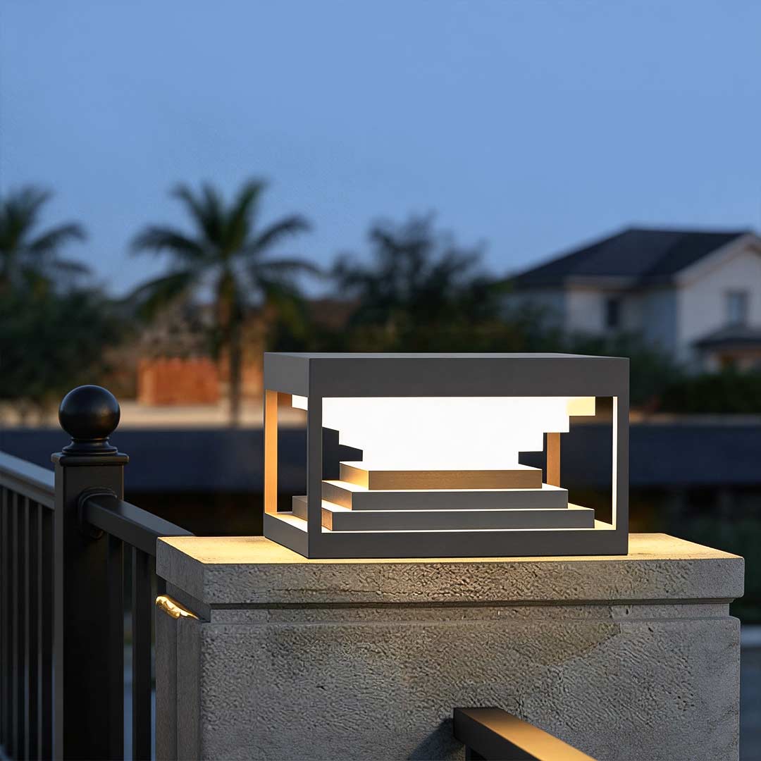 Square pillar lights illuminating a modern outdoor pillar with warm ambient glow.