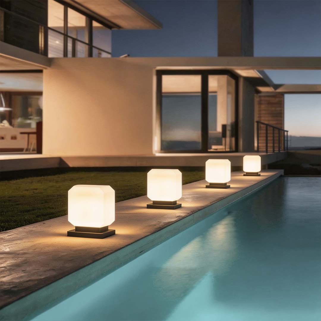 Square pillar lights with a modern design, illuminating a poolside area at night.