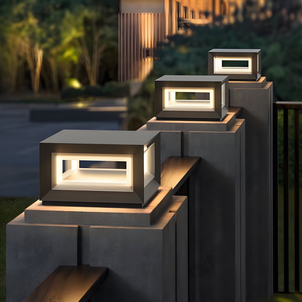 Minimalist square pillar lights arranged along a stepped wall, casting warm illumination across a sleek outdoor boundary design.