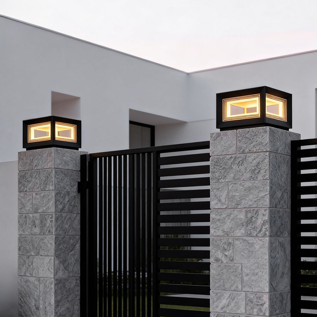 Square pillar lights installed on stone columns beside a metal gate, providing clean architectural lighting for a modern home exterior.