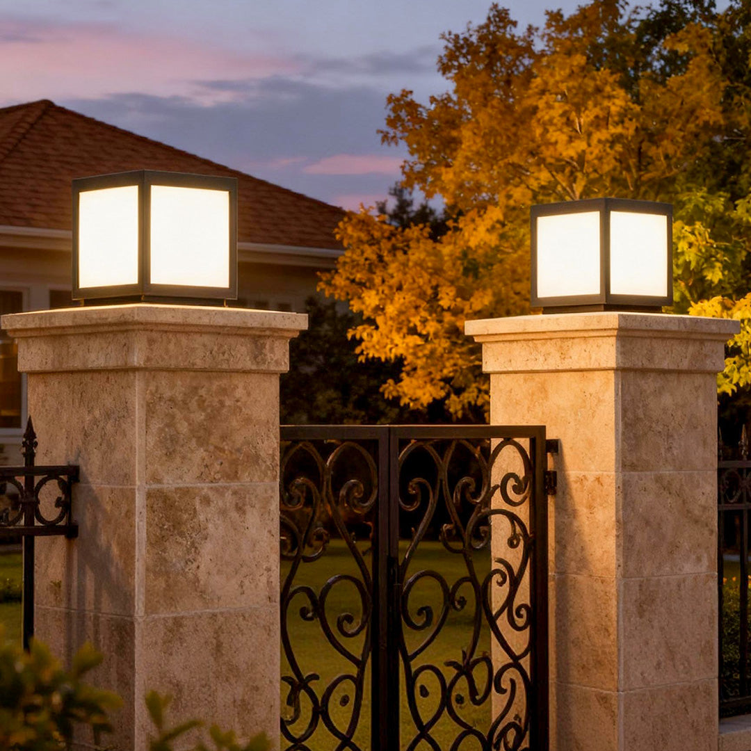 Square pillar lights mounted on stone columns at a gated entrance, offering a warm and inviting glow for outdoor spaces.