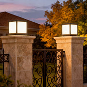 Square pillar lights mounted on stone columns at a gated entrance, offering a warm and inviting glow for outdoor spaces.