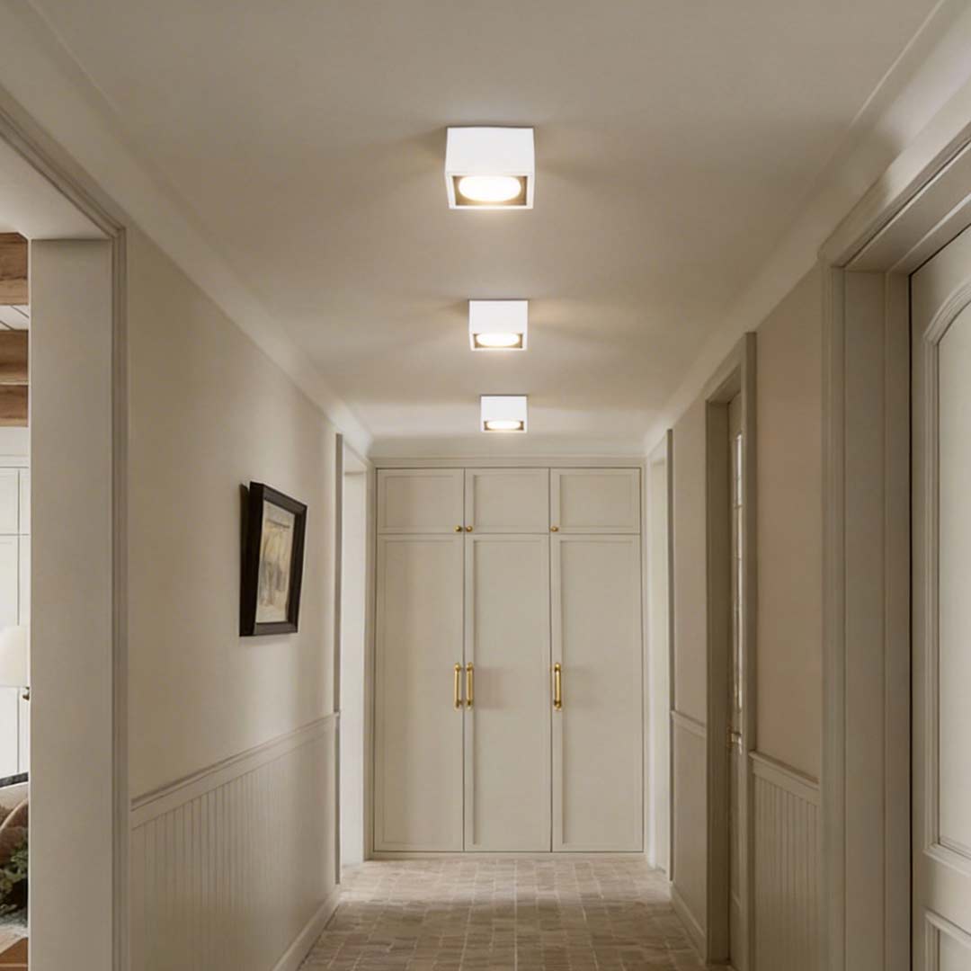 Square recessed downlight illuminating a modern hallway with soft ambient glow.