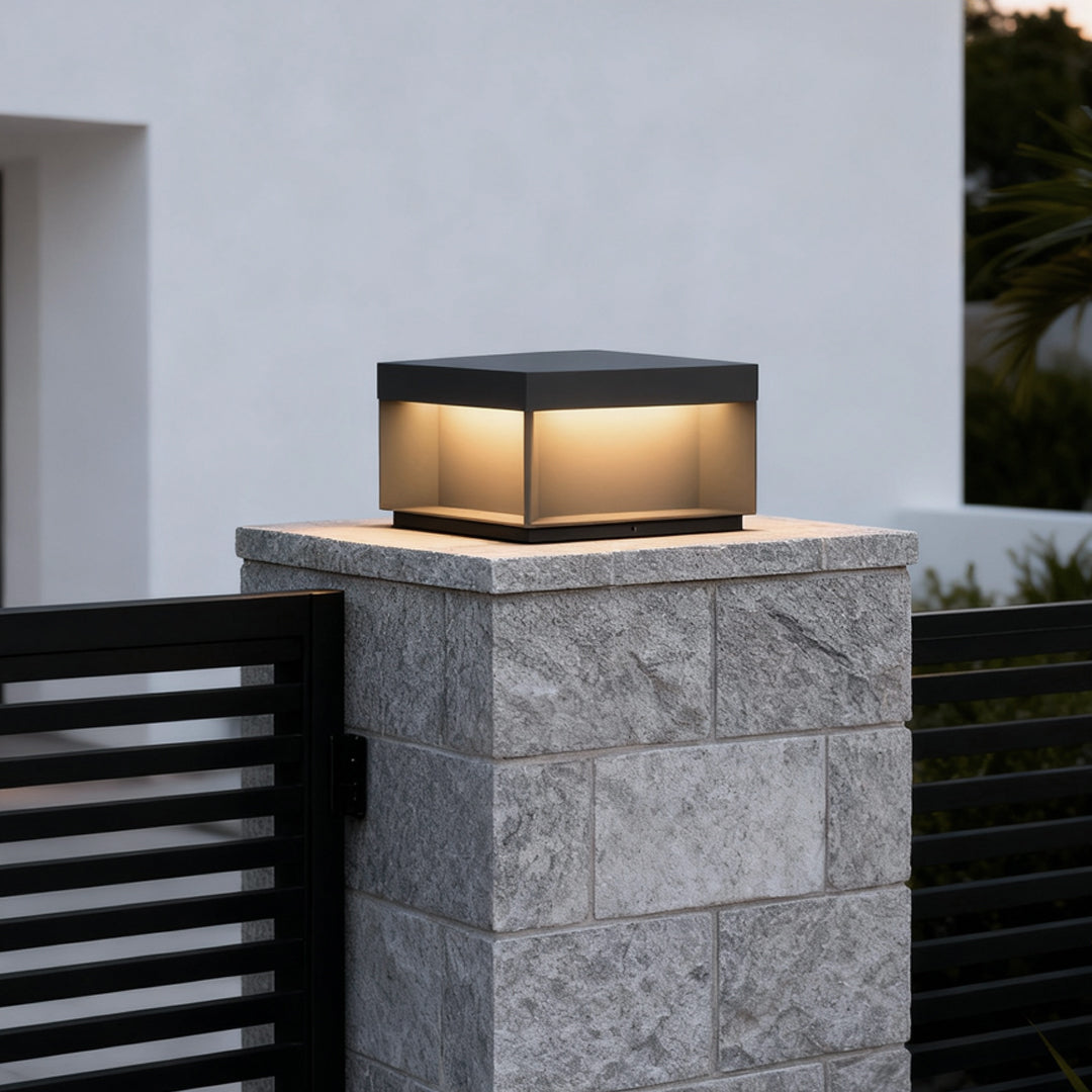 Square solar deck light placed on tall stone column for contemporary outdoor lighting.