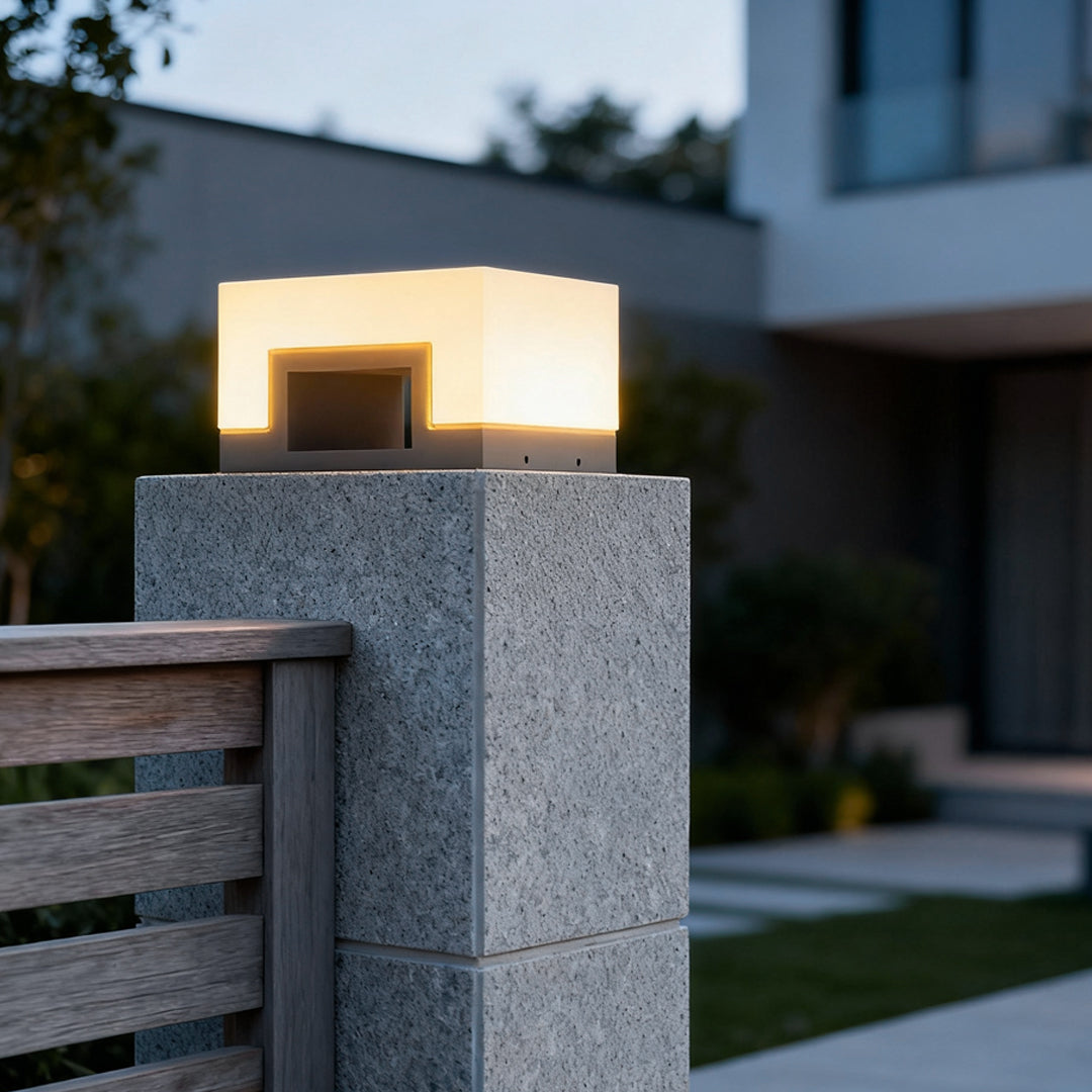 Square solar lawn light on concrete post providing soft ambient outdoor lighting.