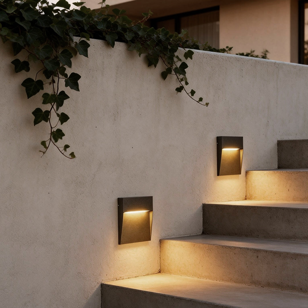 Square stair lights embedded in a garden wall, illuminating steps with warm, subtle glow.