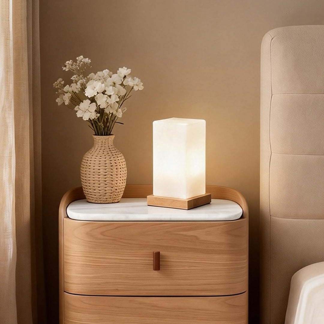 Square table light on a bedside cabinet providing soft warm light for a bedroom.