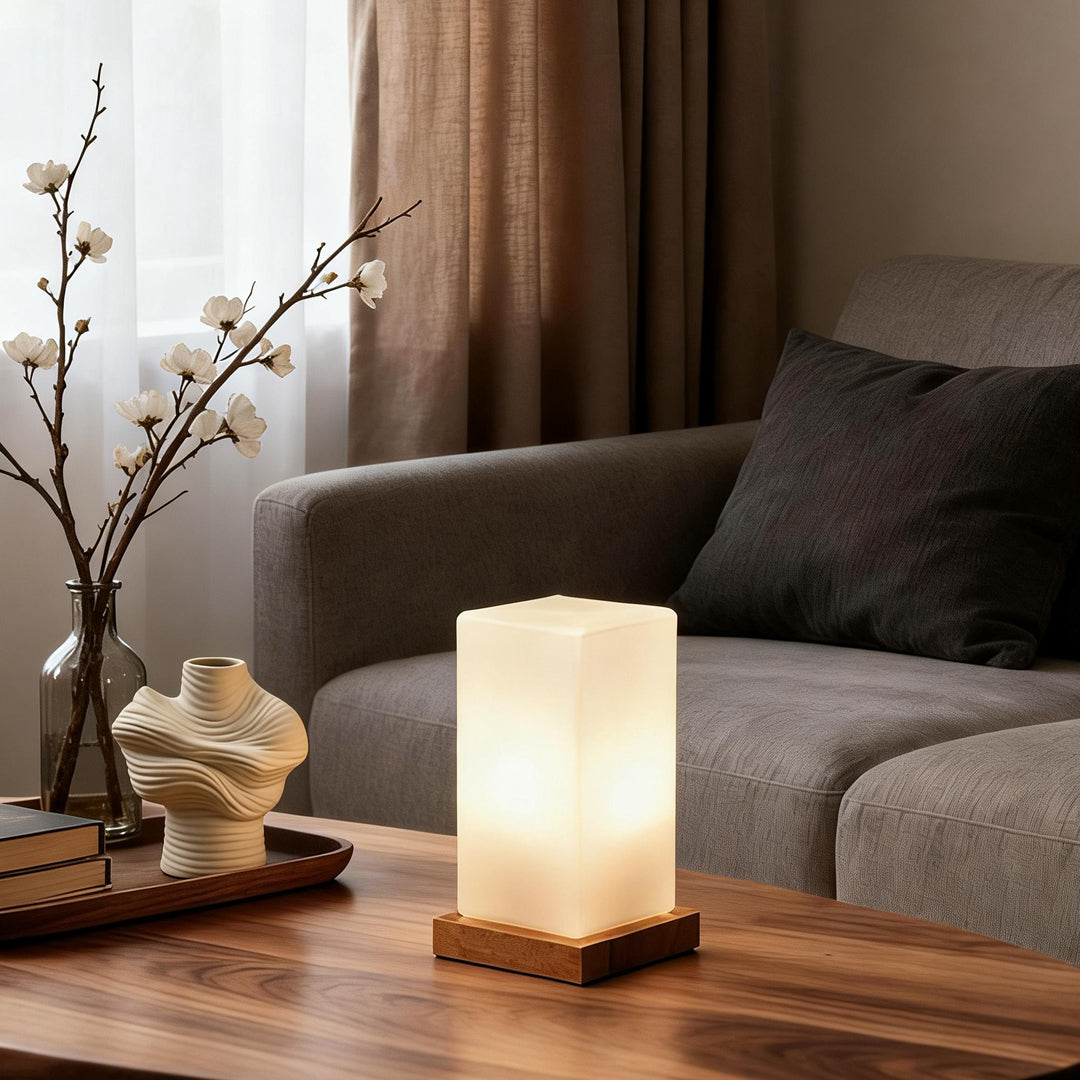 Square table light placed on a wooden coffee table creating warm ambient lighting in a living room.