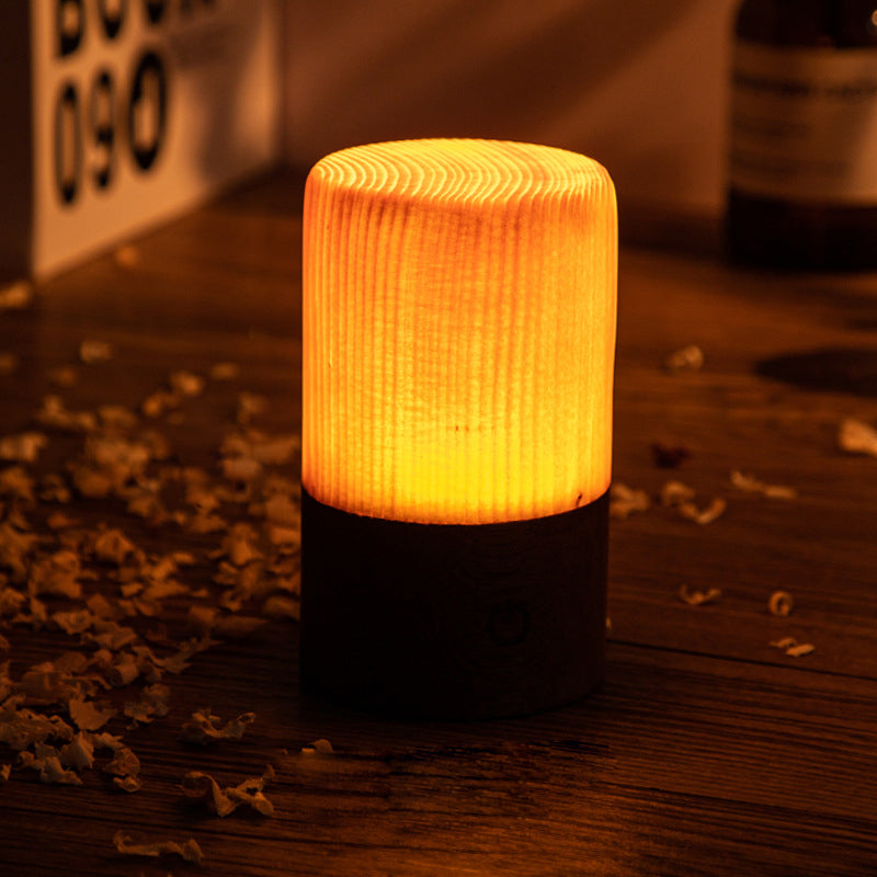 Square wood lamp in cube shape, glowing softly on a wooden table.