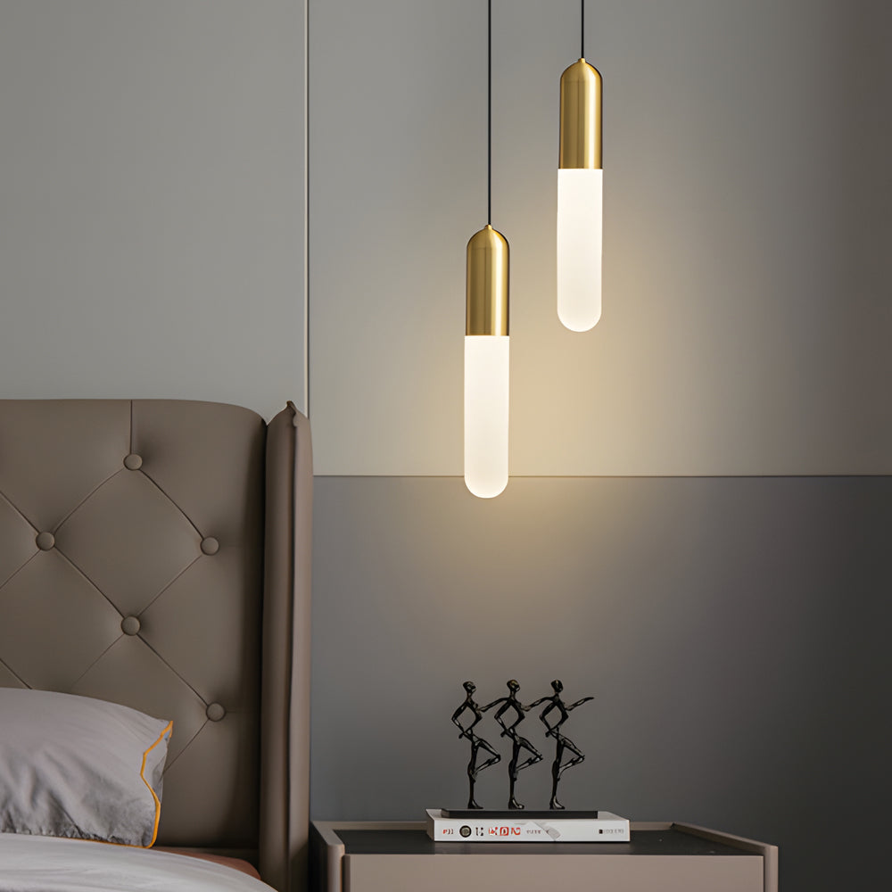 Staggered Gold Capsule Pendant Light duo used as elegant bedside lamps in a modern grey bedroom.