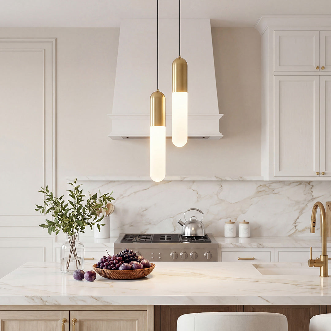 Staggered duo of Gold Capsule Pendant Light fixtures over a bright luxury marble kitchen island.