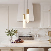 Staggered duo of Gold Capsule Pendant Light fixtures over a bright luxury marble kitchen island.