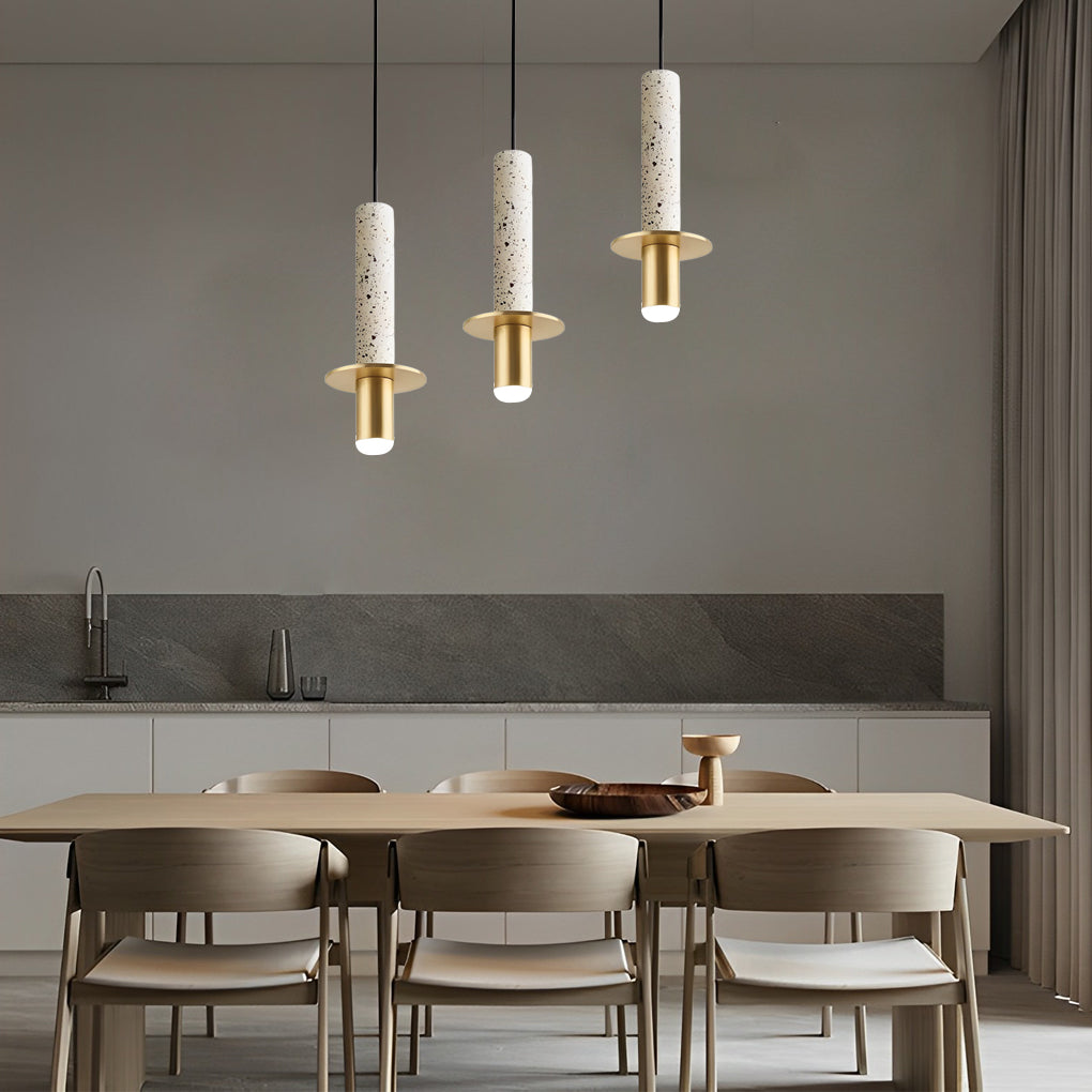 Trio of white terrazzo cylinder pendant lights at staggered heights over a modern dining table.