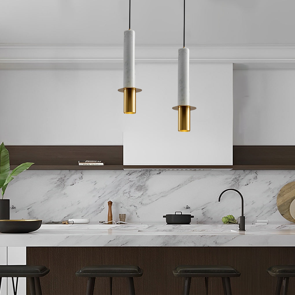 Staggered duo of white terrazzo cylinder pendant lights with gold over a marble kitchen island.