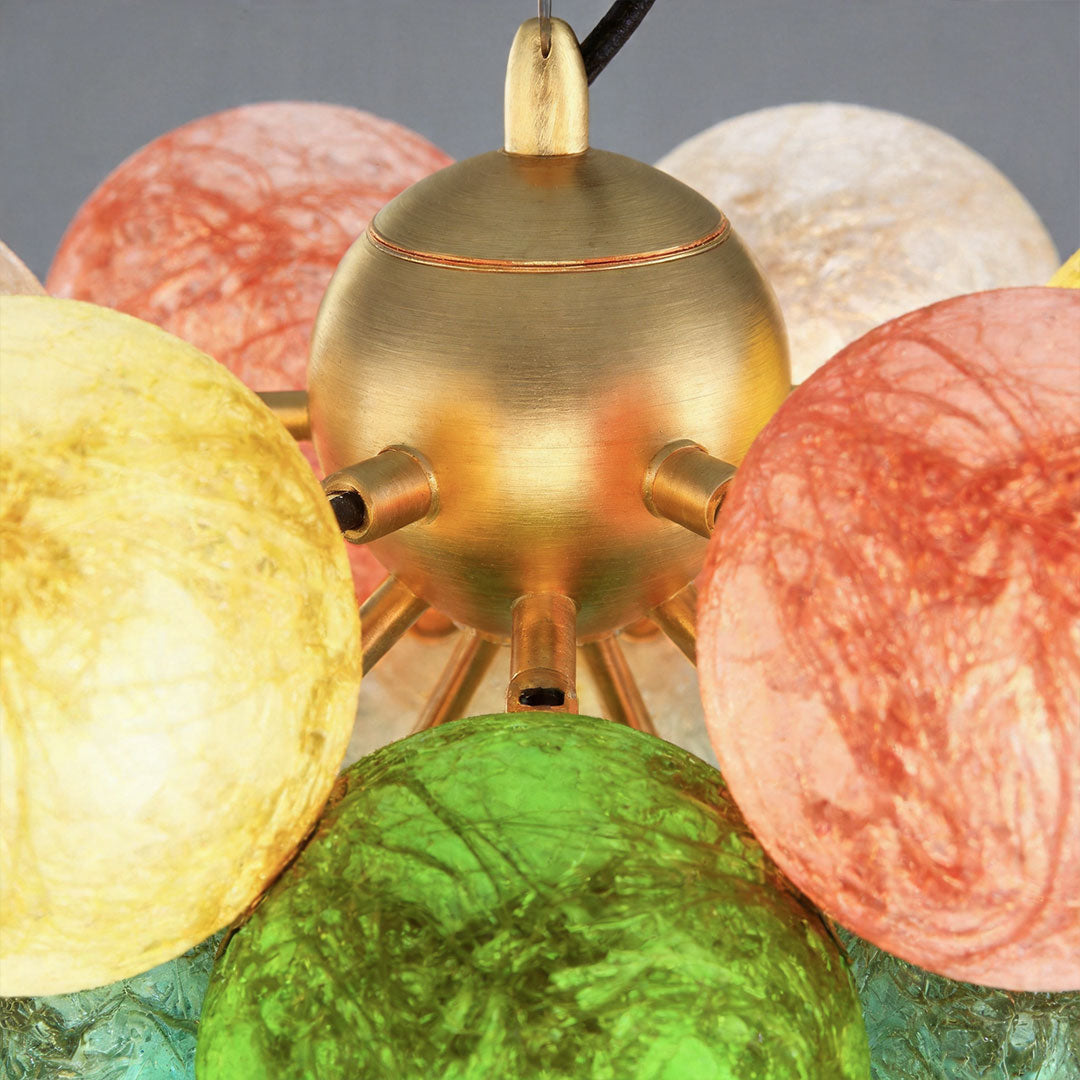 Close-up of stained glass chandelier globes with textured colorful glass and brass frame details.