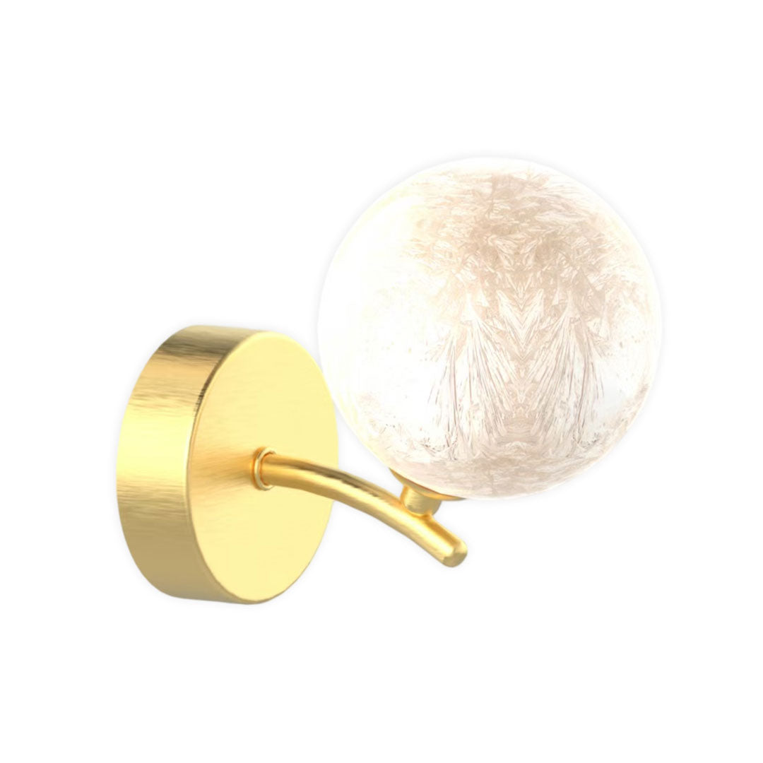 Clear stained glass globe wall light with soft warm glow on brass fixture.
