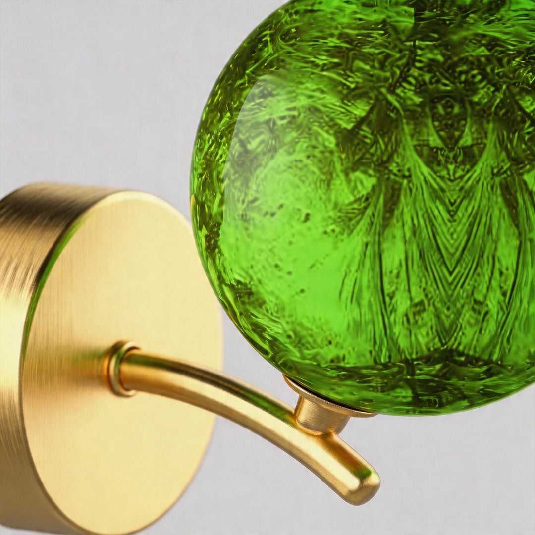 Close-up of green textured stained glass globe wall light with illuminated surface.