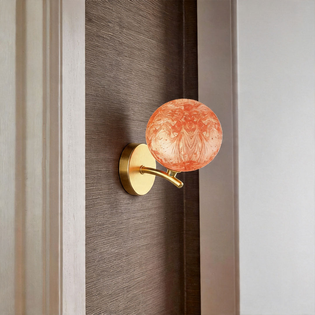 Red stained glass globe wall light mounted beside bed creating warm ambient lighting.