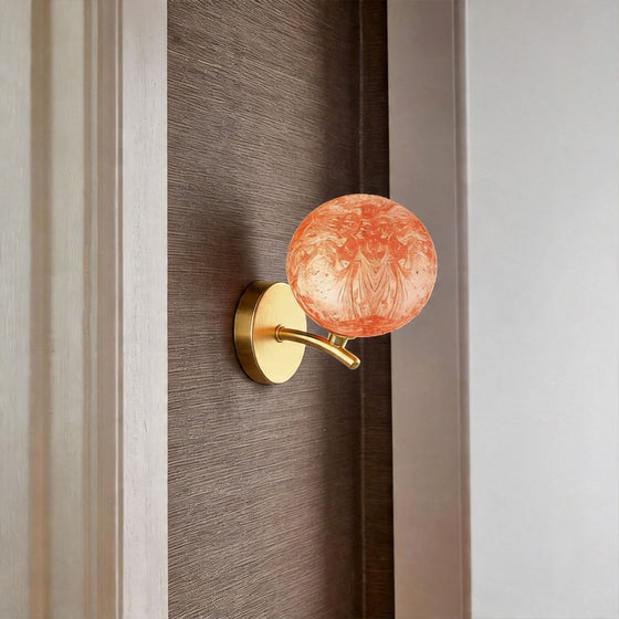 Red stained glass globe wall light mounted beside bed creating warm ambient lighting.