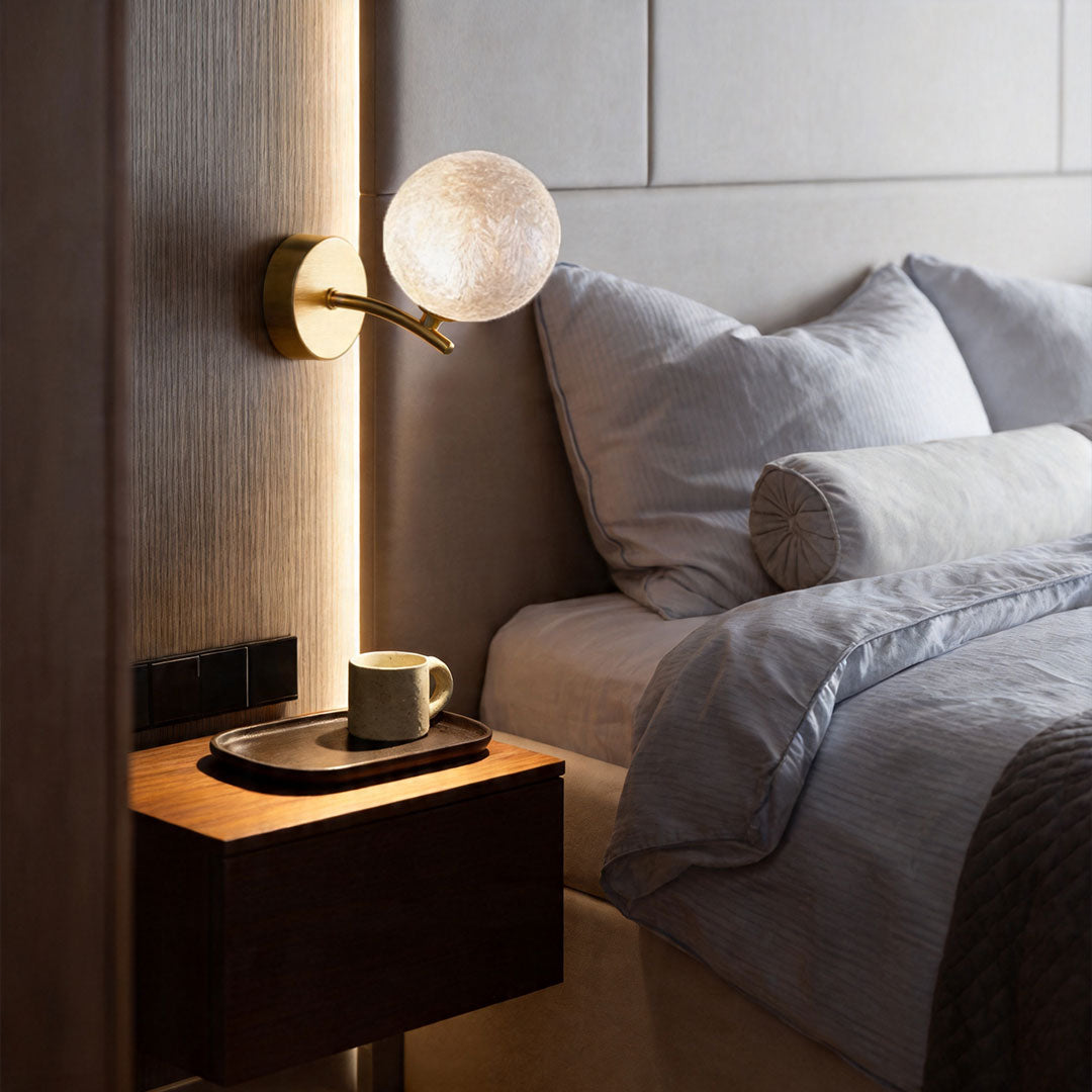 White stained glass wall sconce installed above bedside table with soft glow.