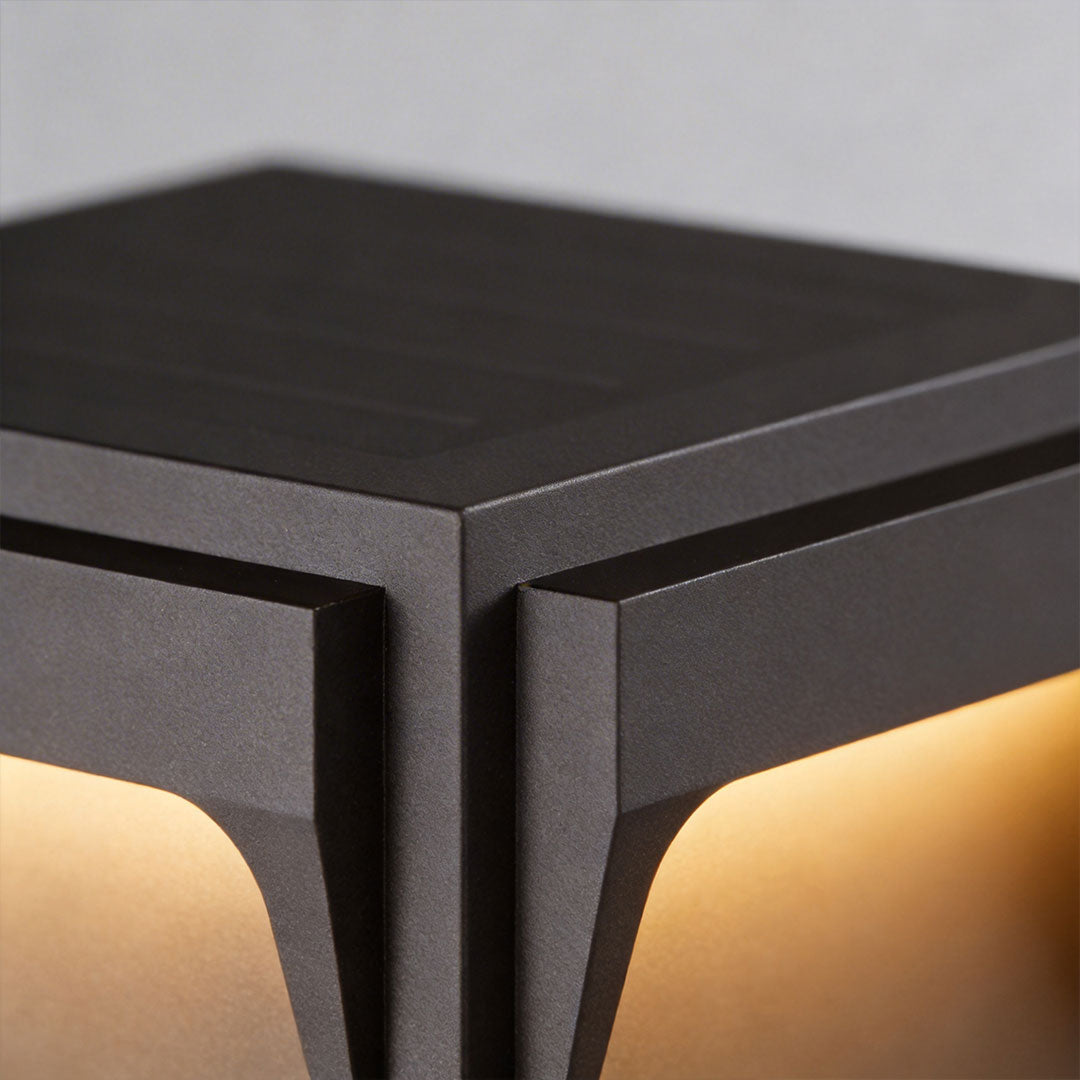 Stainless steel outdoor pillar light with a unique angular design and illuminated base.