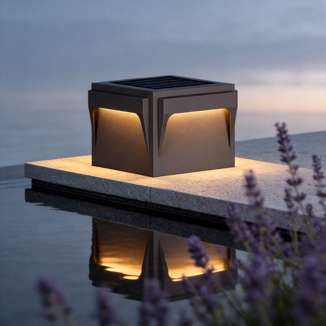 Close-up of a stainless steel outdoor pillar light with a geometric design and warm glow.
