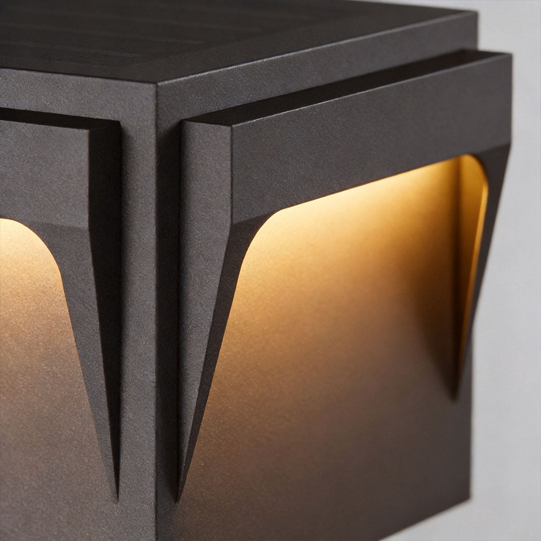 Stainless steel outdoor pillar light with a minimalist design, casting a soft glow on a stone surface.