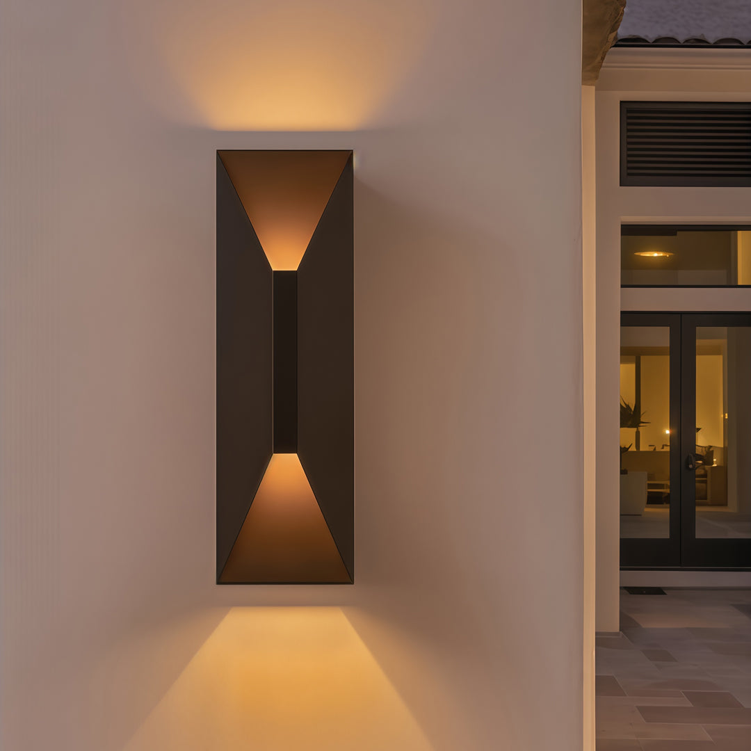 Stainless steel up and down wall light installed in a minimal hallway exterior, producing soft vertical light beams.