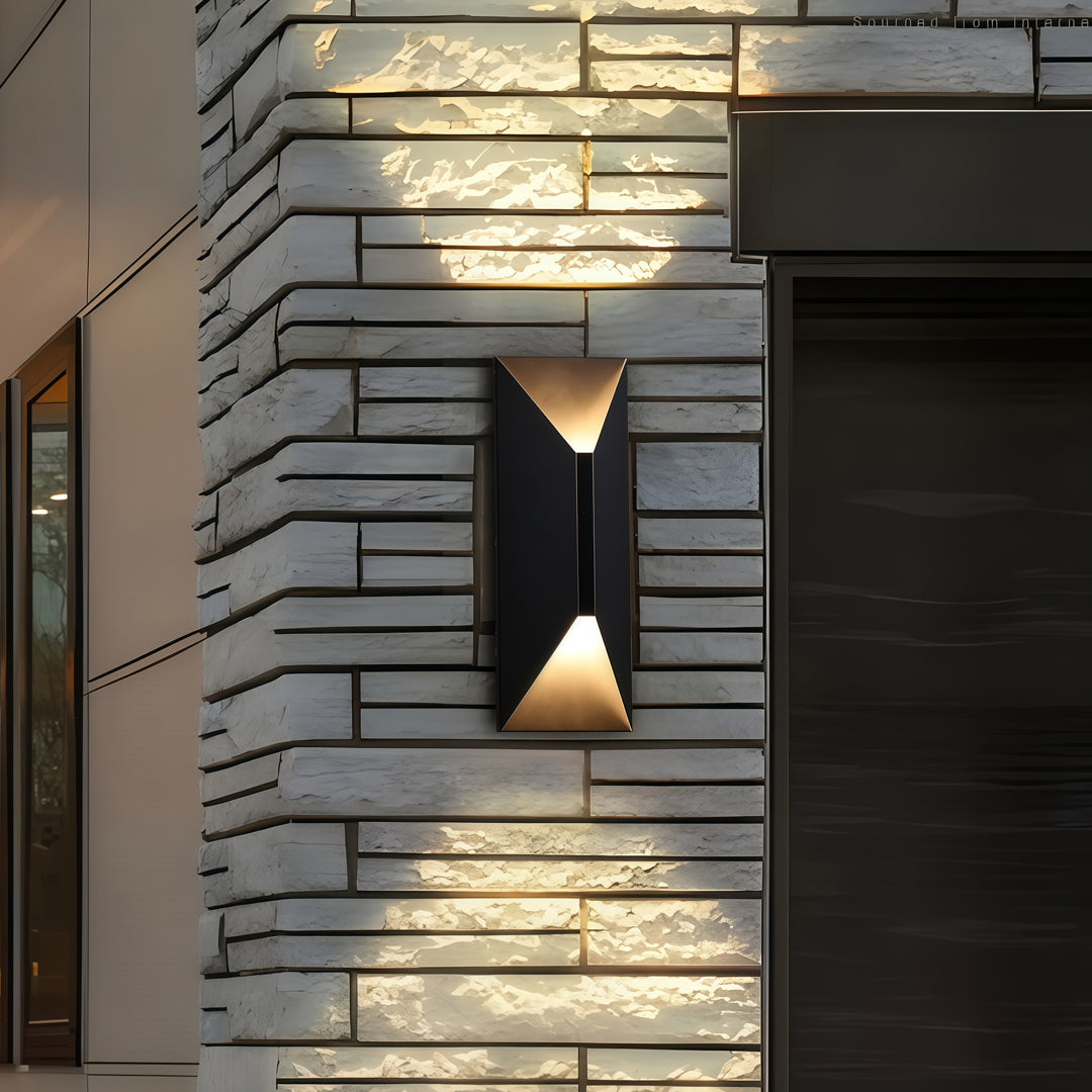 Architectural stainless steel up and down wall light mounted on textured stone siding, creating striking layered illumination.