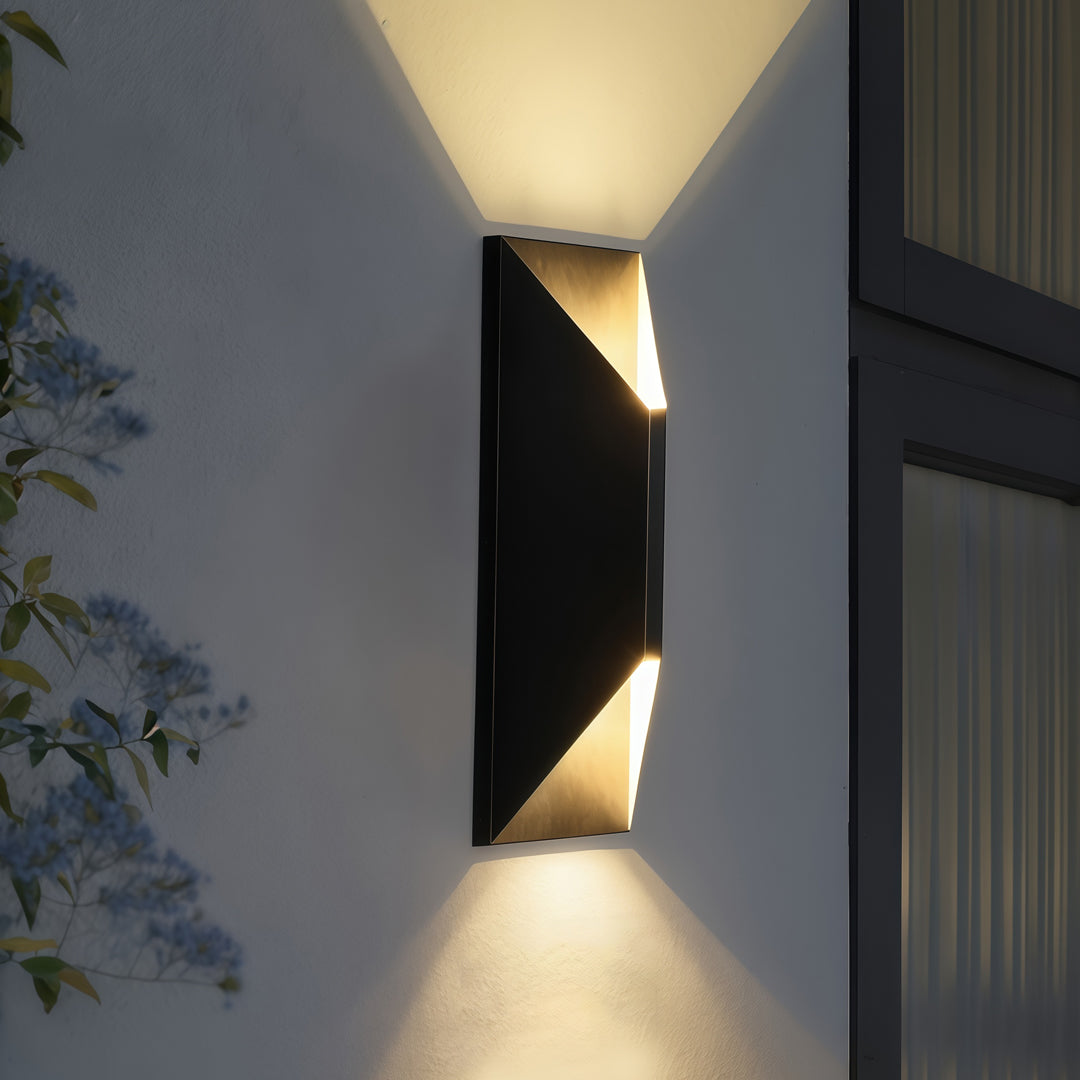Contemporary stainless steel up and down wall light casting warm dual-beam illumination on a white exterior wall.