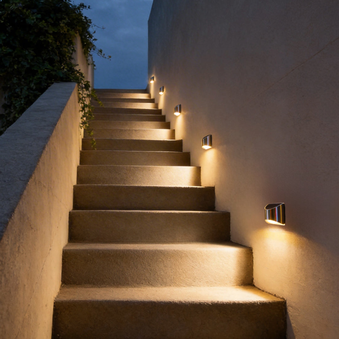 Stainless steel wall lamp mounted on a wall, providing ambient lighting for garden stairs.