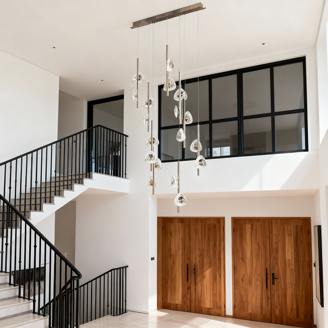 Staircase crystal chandelier suspended in contemporary two-story space with wooden doors and modern architectural elements
