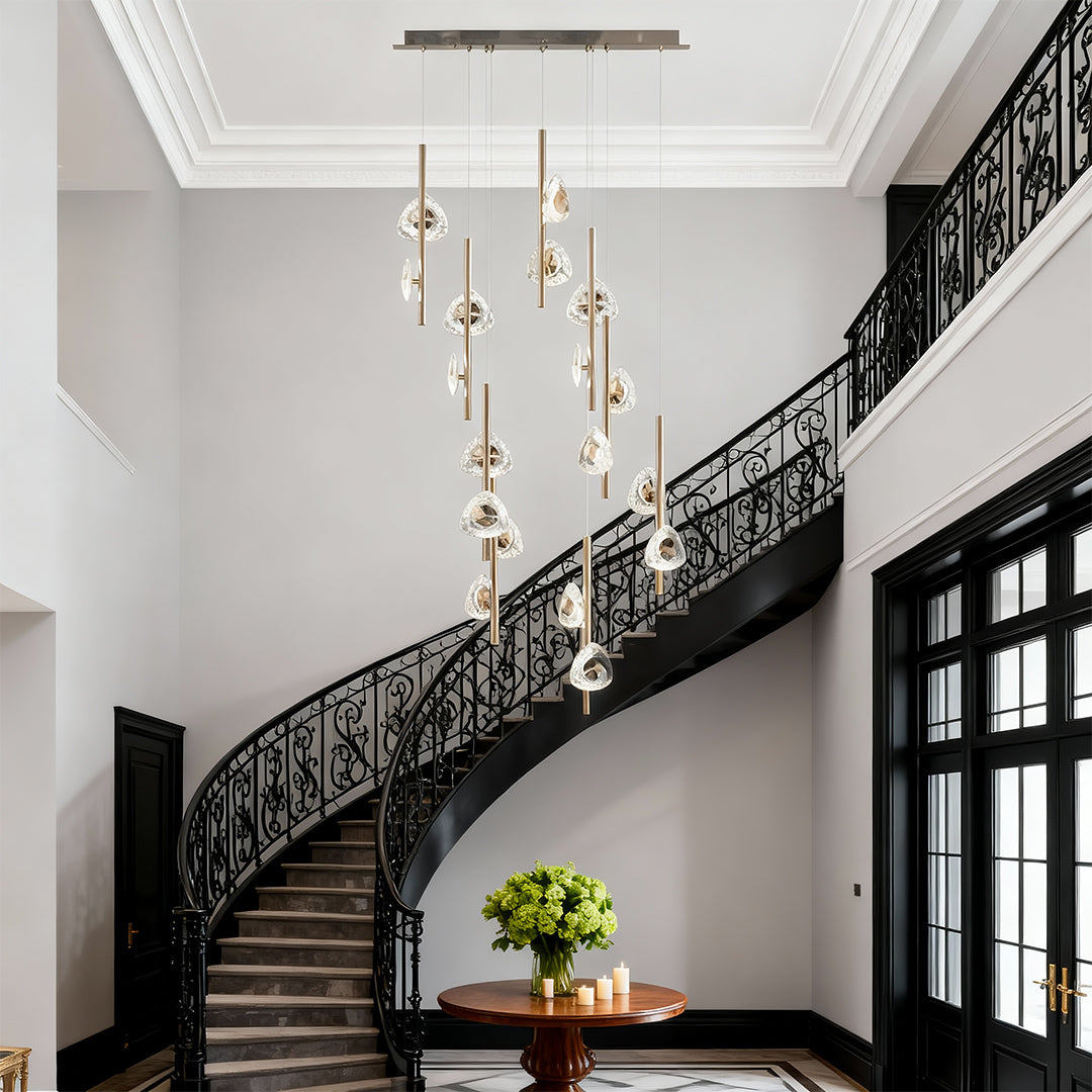 Staircase crystal chandelier creating dramatic focal point in grand foyer with ornate black iron staircase railings