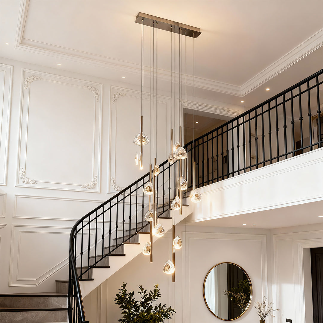 Staircase crystal chandelier illuminating elegant double-height entryway with curved staircase and classic architectural details