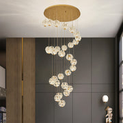 Spiral crystal chandelier installed in a tall modern staircase area.