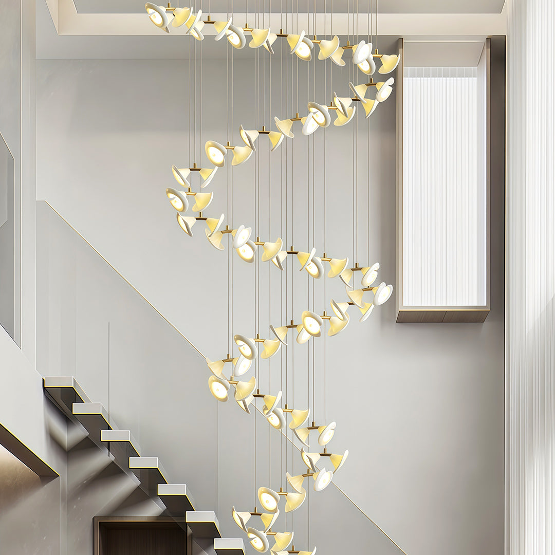 Modern brass chandelier installed along a spiral staircase.