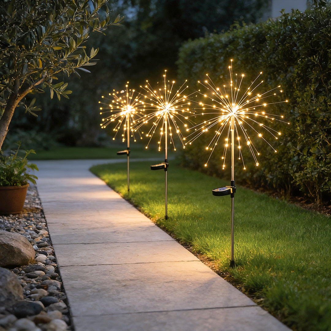 Starburst garden lights lining a stone pathway, casting a warm glow on the surrounding greenery.