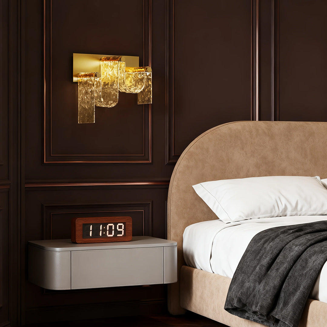 Statement gold wall light mounted above dark wood headboard in rich brown bedroom interior