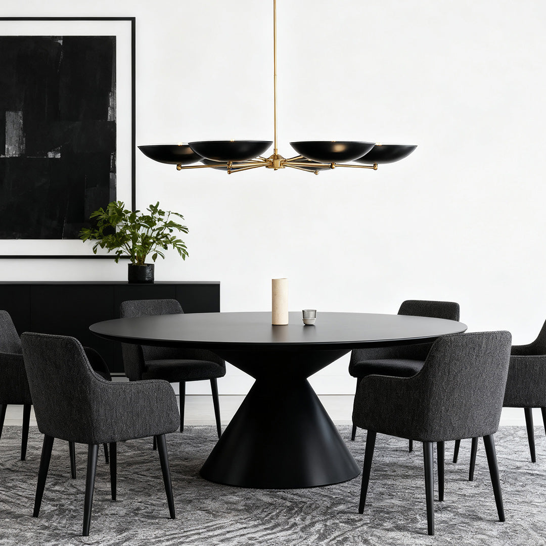 Statement black and gold chandeliers over a round black dining table, complementing dark, textured decor and plush gray seating.