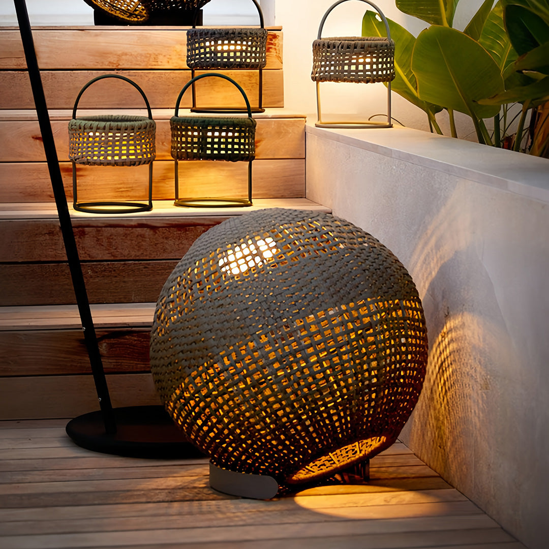Statement outdoor globe lantern sitting on stone steps, highlighting the dark, weather-resistant woven texture.
