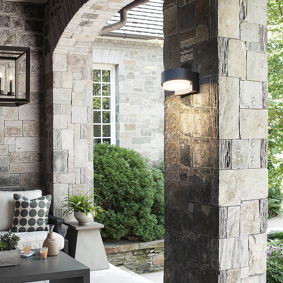 Elegant lights for outdoor wall illuminating a stone archway walkway in a stylish garden setting.